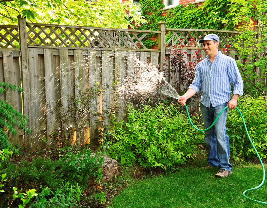 man watering his backyard garden