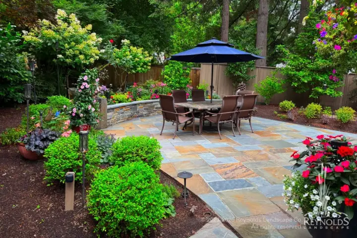 colorful dimensional flagstone backyard patio bordered by mortared seatwall and surrounded by garden plantings