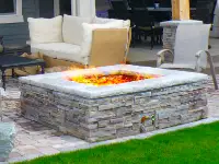 Unique square gas pire pit on paver patio.