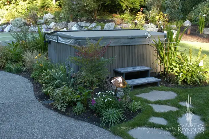Hot tub surrounded by PNW garden plantings with flagstone path and landscape lighting