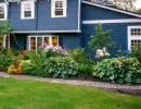 Front yard garden bed with hydrangeas, hostas, and mixed perennials along a navy blue home exterior