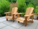 Two cedar Adirondack chairs on a paver patio surrounded by ornamental grasses and mixed evergreen shrubs in a Pacific Northwest garden