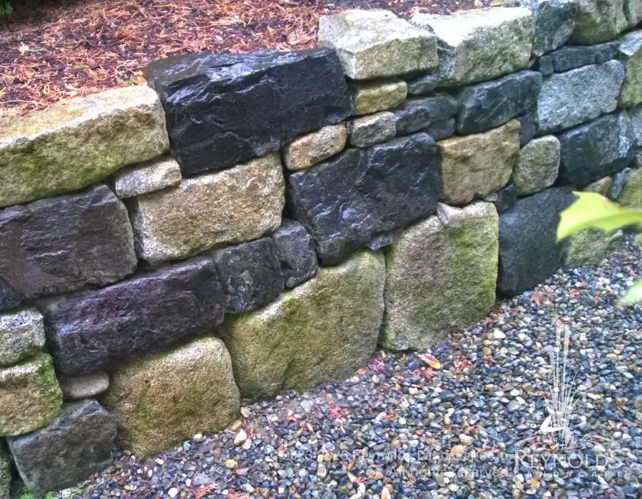 Mixed granite and basalt natural boulder retaining wall with bark mulch ground cover