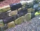 Mixed granite and basalt natural boulder retaining wall with bark mulch ground cover