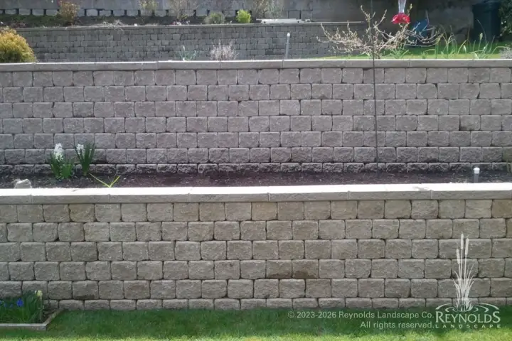 Tiered concrete block retaining walls with narrow planting strip and manicured lawn alongside residential property