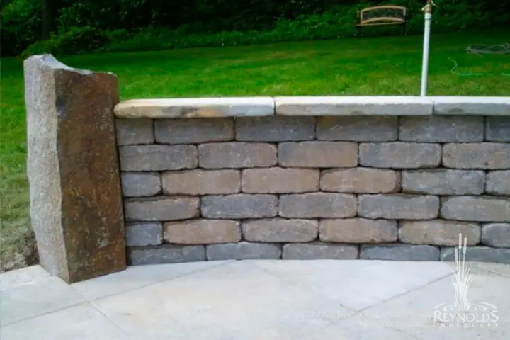 Concrete block retaining wall with pillar end cap and manicured lawn on upper level